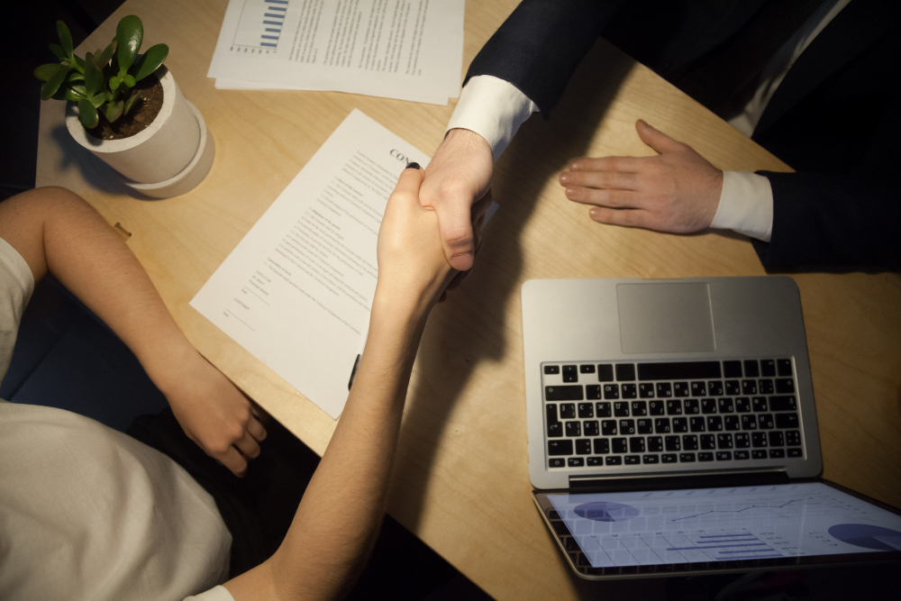 Pessoas fechando contrato de exclusividade e dando as mãos